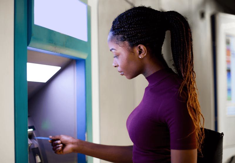 A woman approaching an ATM with her bank card